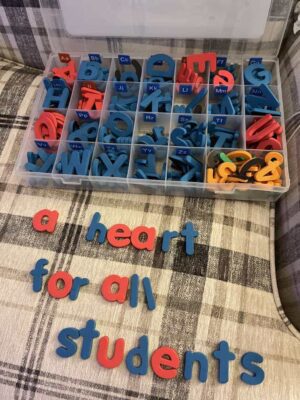 Play-based phonics tools for kids magnetic letters lying on a plaid chair spelling the words A Heart for All Students