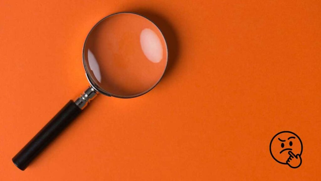Magnifying glass lying on orange background.